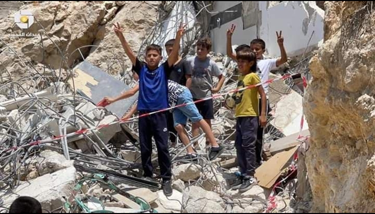 يرفعون شارة النصر على ركام منزلهم المهدم